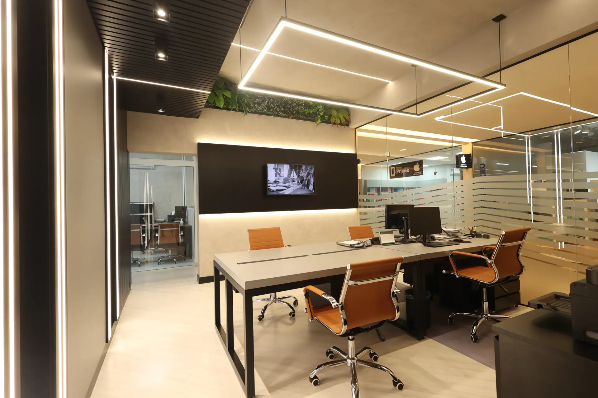 Sala de trabalho da sede Tricon, com mesa, cadeiras e divisórias de vidro